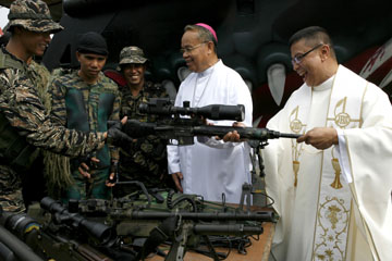 Priests check the firearms of Marines who will be sent to Basilan province in southern Philippines during the 110th founding anniversary of the Philippine Navy in Manila